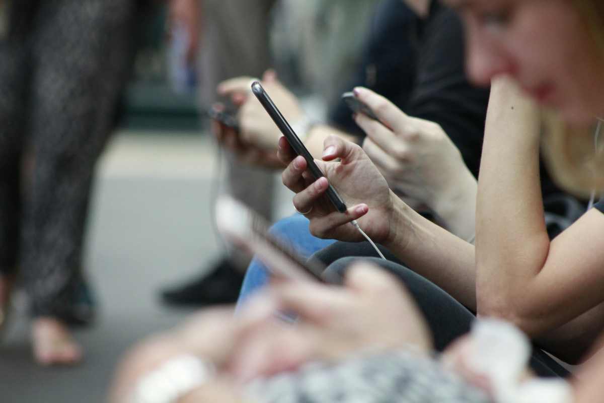 Una fila di persone con in mano lo smartphone