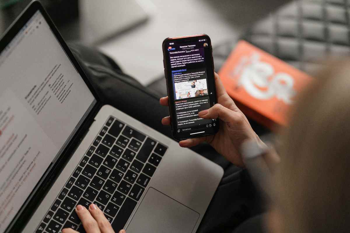 Uomo che guarda uno smartphone mentre è al pc